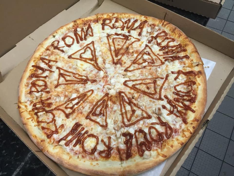Cheese pizza decorated with Roma written in sauce, boxed to go