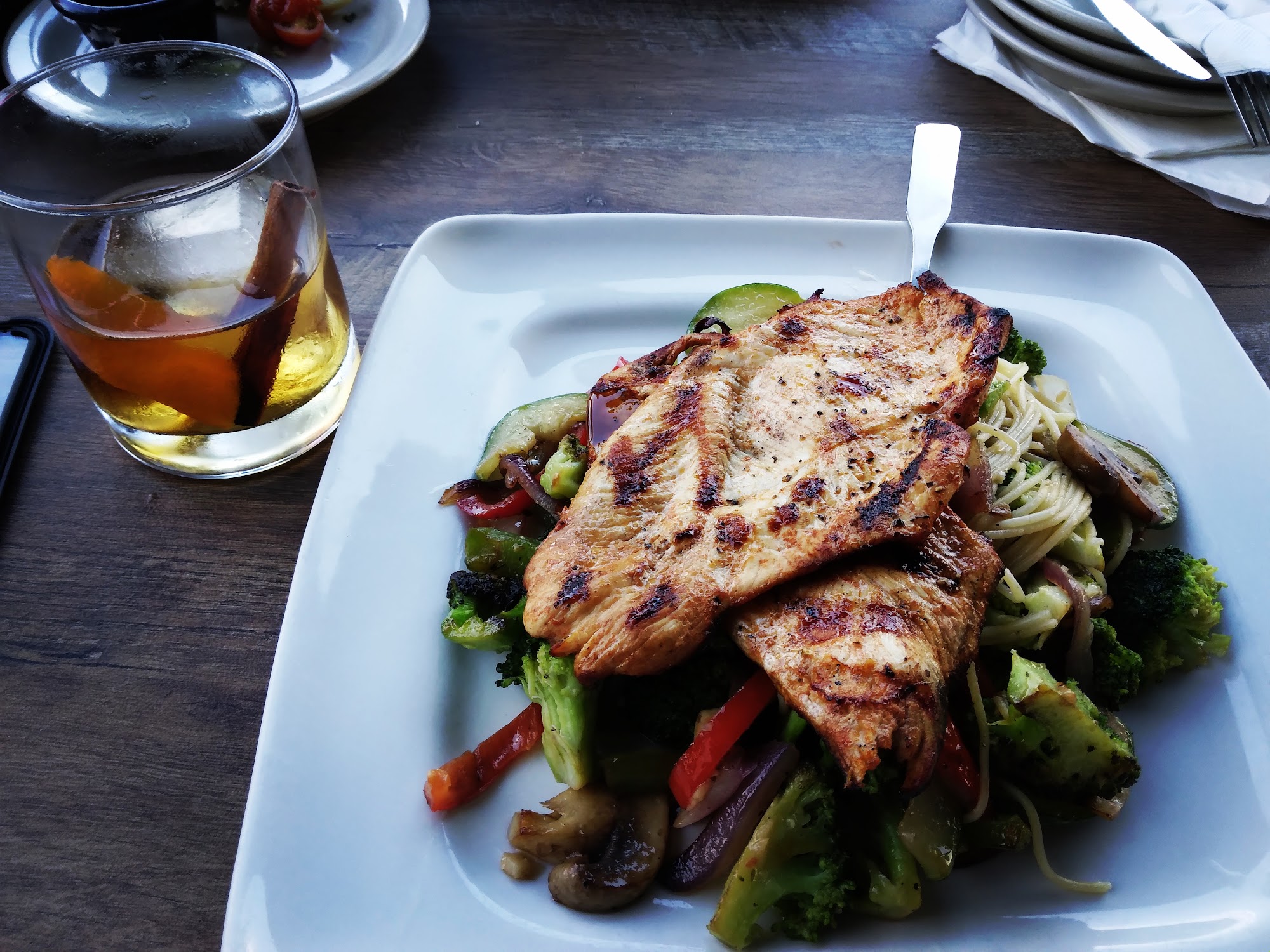 Grilled chicken over pasta with broccoli, red pepper, mushroom and red onion