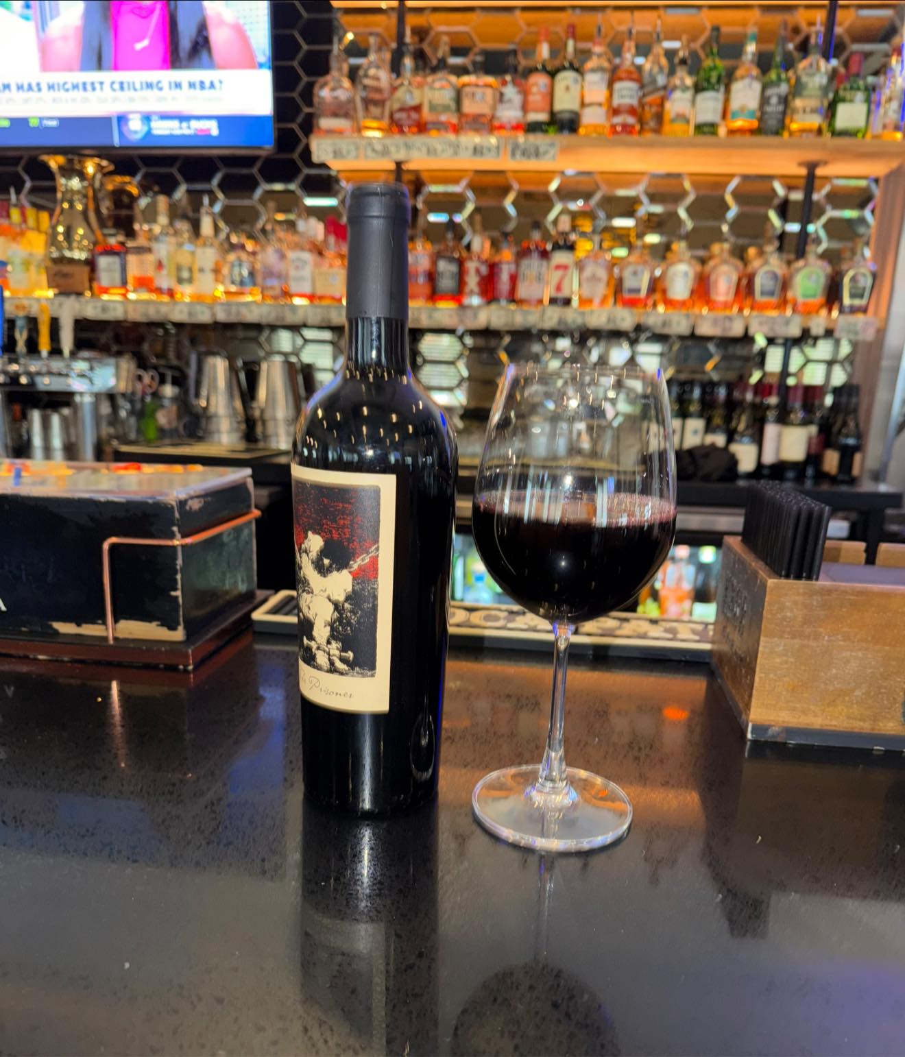 Glass of red wine poured beside the bottle at the bar