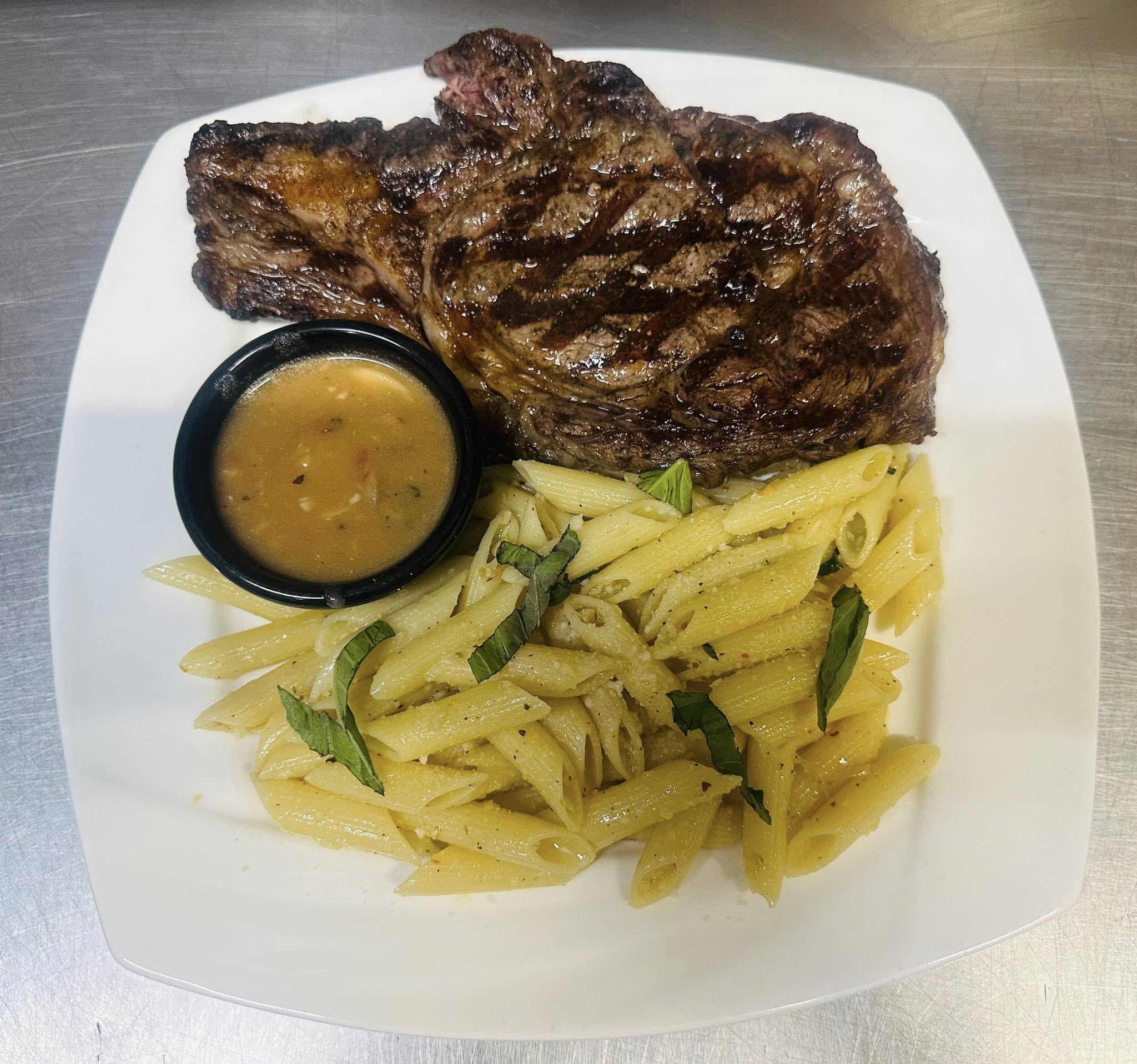 Grilled steak with basil parmesan penne and a side sauce